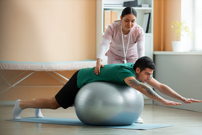 Physical therapist assisting a patient with stability ball exercises during general physical therapy at Flexify Physical Therapy in Allen, TX to improve mobility and recovery.